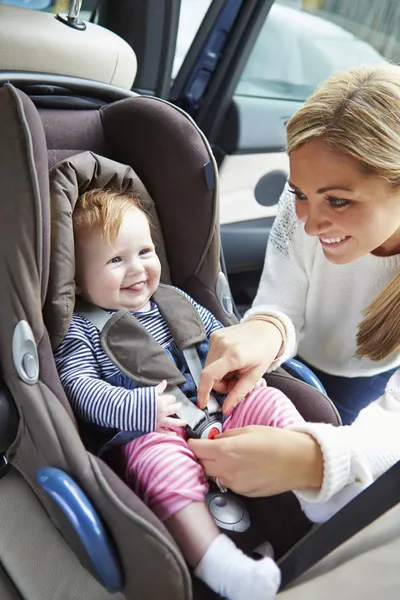 Mutter setzt Baby in Autositz — Stockfoto