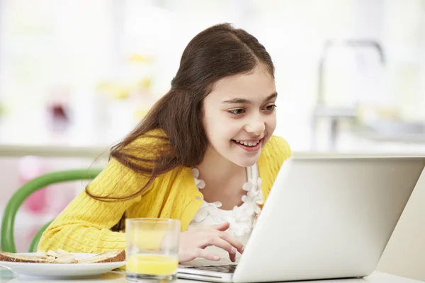 Κορίτσι ισπανικός χρησιμοποιώντας φορητό υπολογιστή που τρώει πρωινό — Φωτογραφία Αρχείου