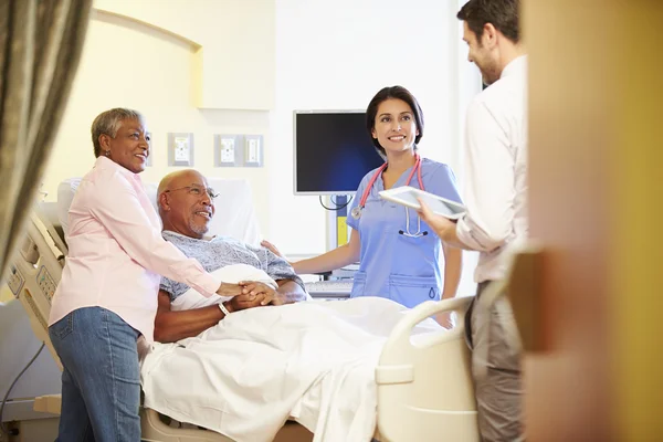 Medisch team ontmoeting met senior koppel in ziekenhuis kamer — Stockfoto