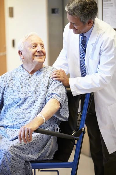 Paciente masculino mayor siendo empujado en silla de ruedas por médico — Foto de Stock