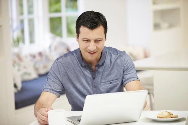 Uomo ispanico che utilizza il computer portatile in cucina a casa — Foto Stock