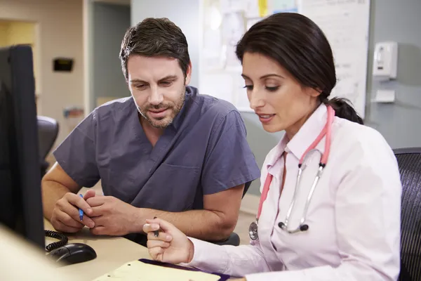 Medico femminile con infermiere di sesso maschile che lavora alla stazione infermieri — Foto Stock