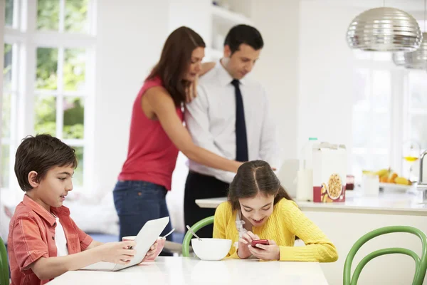 Família usando dispositivos digitais na mesa de café da manhã — Fotografia de Stock