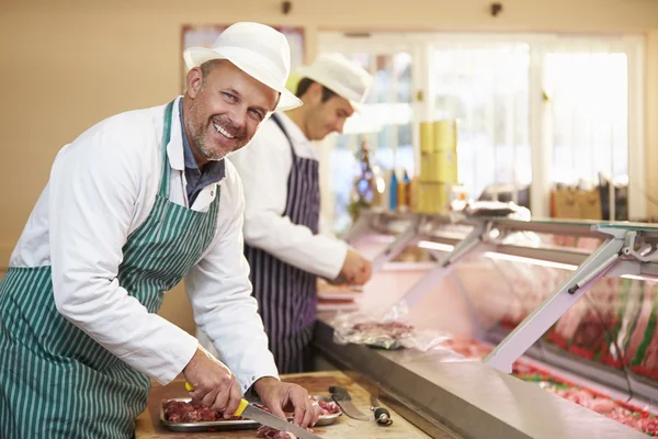 Twee slagers voorbereiding van vlees in winkel — Stockfoto