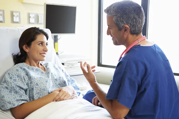 Manliga sjuksköterska prata med kvinnliga tålmodig i sjukhussal — Stockfoto