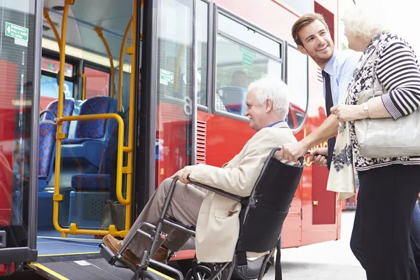 Autista che aiuta il bus anziano del bordo della coppia tramite la rampa della sedia a rotelle — Foto Stock