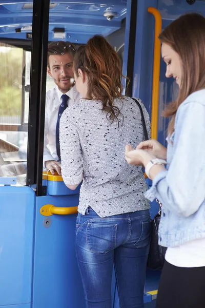 Duas mulheres jovens ônibus de embarque e compra de ingresso — Fotografia de Stock