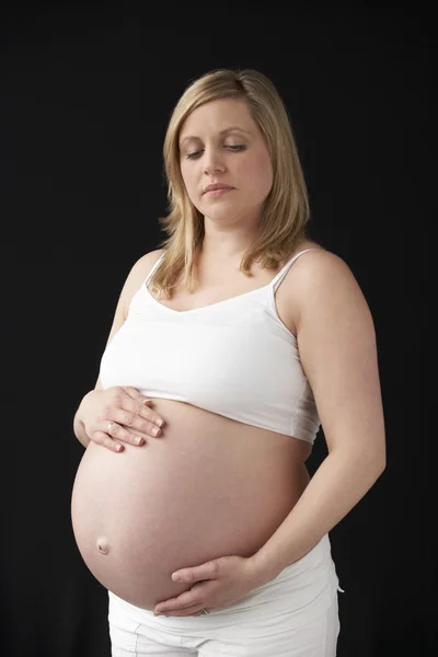 Porträt einer im neunten Monat schwangeren Frau, die weiß auf schwarzem Rücken trägt — Stockfoto