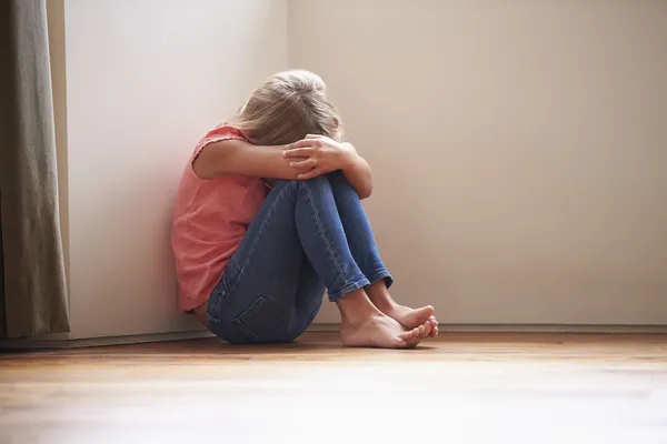 Enfant malheureux assis sur le sol dans le coin à la maison — Photo