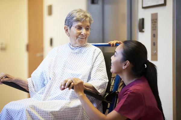 Äldre skjuts kvinnlig patient i rullstol av sjuksköterska — Stockfoto