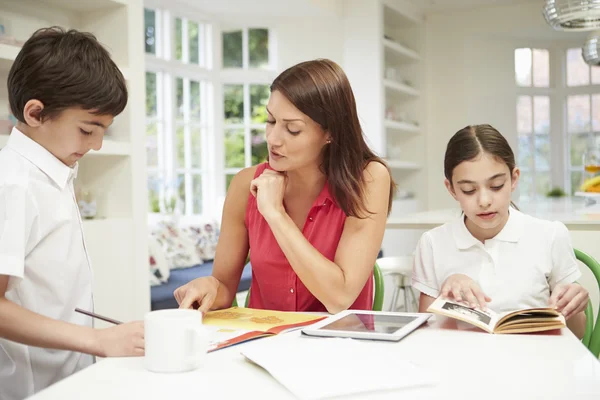 Mutter hilft Kindern bei Hausaufgaben mit digitalem Tablet — Stockfoto