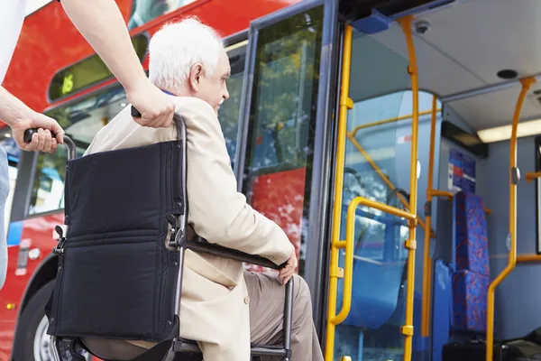 Seniorenpaar steigt über Rollstuhlzugangsrampe in Bus ein — Stockfoto