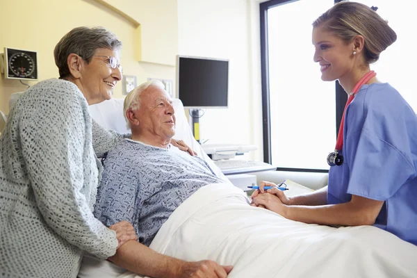 Sjuksköterska talar till äldre par i sjukhussal — Stockfoto