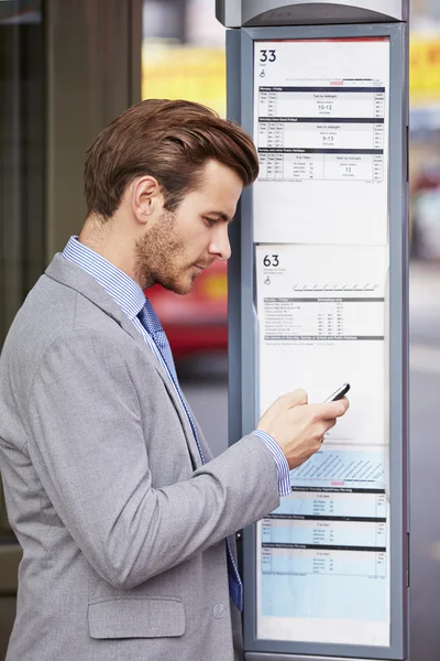 Uomo d'affari alla fermata dell'autobus con telefono cellulare — Foto Stock