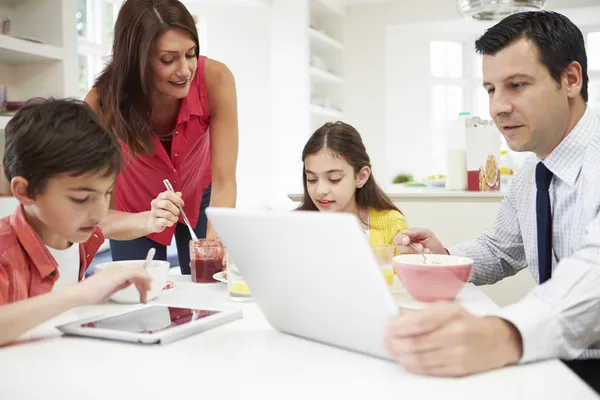 Familie nutzt digitale Geräte am Frühstückstisch — Stockfoto