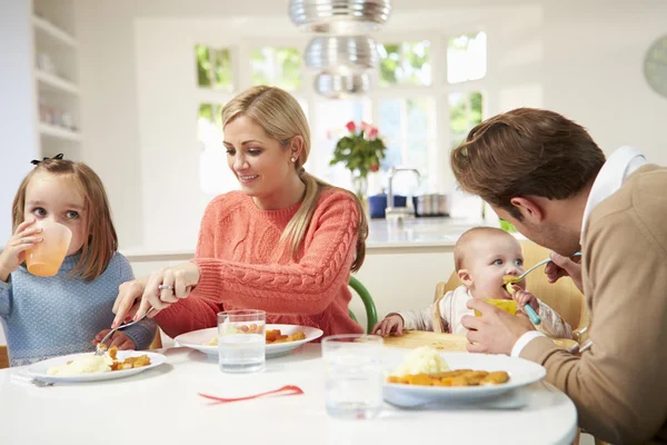 Familia con bebé pequeño comiendo comida en casa —  Fotos de Stock