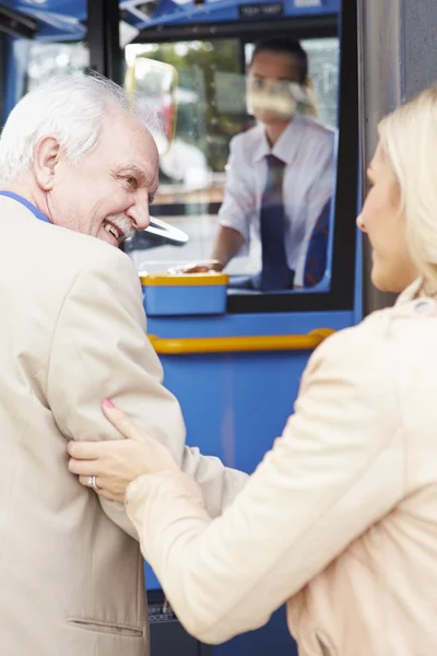 Женщина помогает старшему мужчине сесть в автобус — стоковое фото