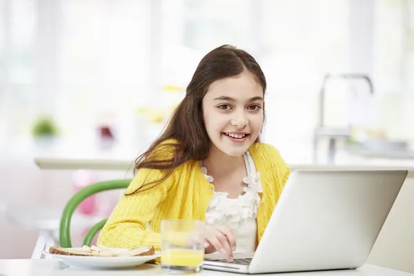 Ispanico ragazza utilizzando computer portatile mangiare colazione — Foto Stock