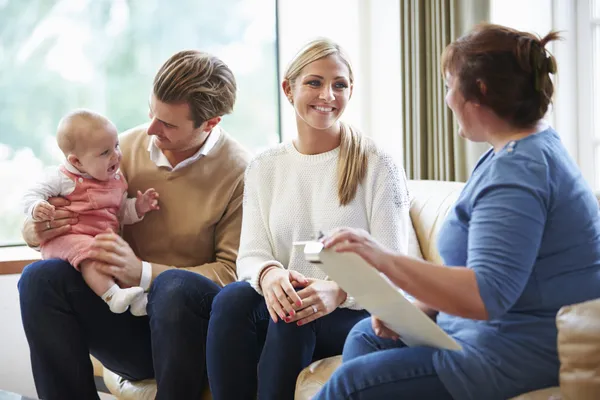 Visitante de salud hablando con la familia con el bebé pequeño — Foto de Stock