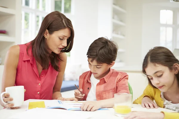Matka pomáhá dětem s domácím úkolem — Stock fotografie