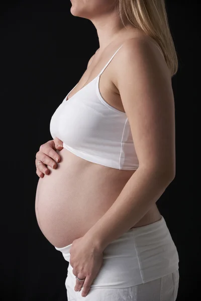 Primer plano retrato de 5 meses mujer embarazada sobre fondo negro — Foto de Stock