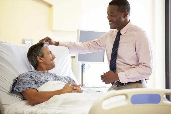 Läkare pratar med manlig patient i sjukhussal — Stockfoto
