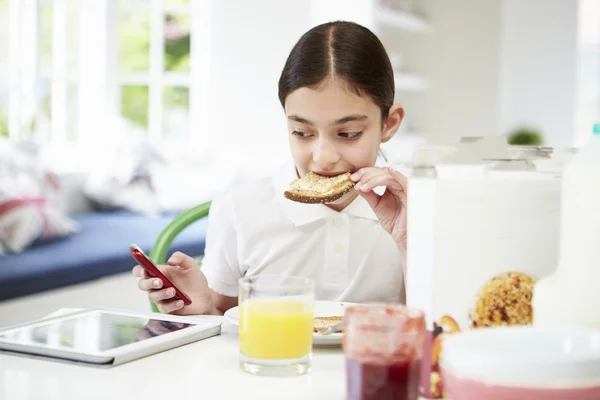 Schülerin mit digitalem Tablet und Handy beim Toast essen — Stockfoto