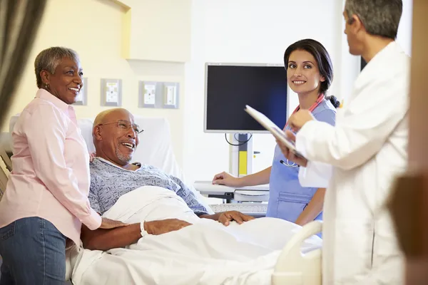 Medisch team ontmoeting met senior koppel in ziekenhuis kamer — Stockfoto