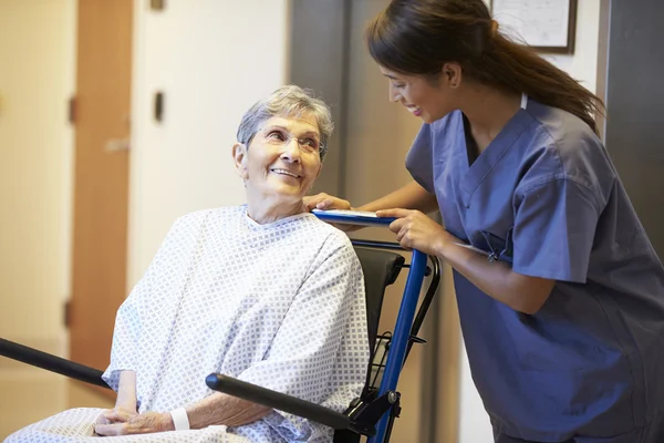 Äldre skjuts kvinnlig patient i rullstol av sjuksköterska — Stockfoto