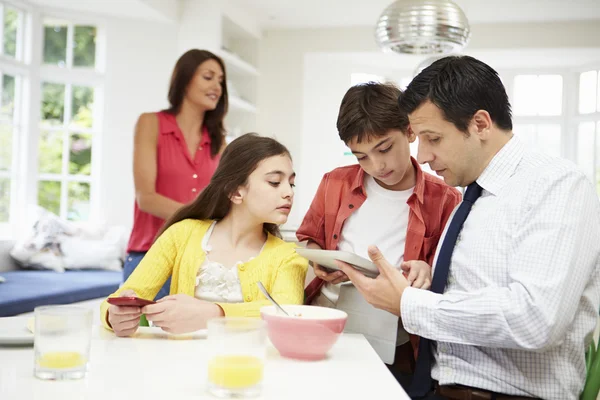 Família usando dispositivos digitais na mesa de café da manhã — Fotografia de Stock