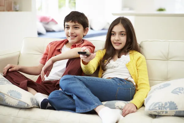 Dos niños hispanos sentados en un sofá viendo televisión juntos — Foto de Stock