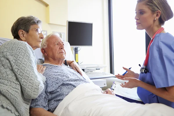 Infermiera parlando con anziano coppia in ospedale stanza — Foto Stock