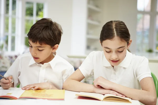 Niños vistiendo uniforme escolar haciendo tareas en la cocina — Foto de Stock