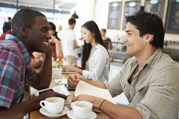 Dos amigos masculinos se reúnen en una cafetería ocupada —  Fotos de Stock