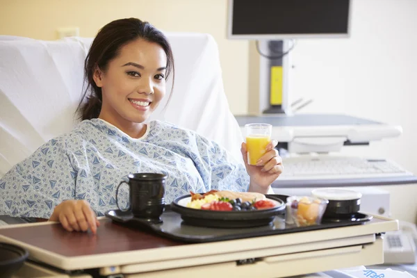 Paciente femenina disfrutando de la comida en la cama del hospital — Foto de Stock