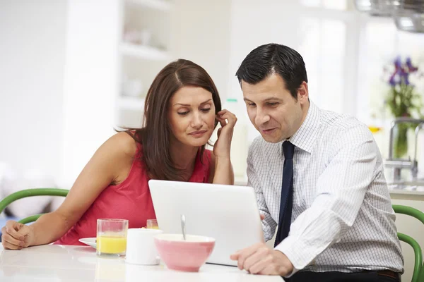 Casal olhando para laptop durante o café da manhã — Fotografia de Stock