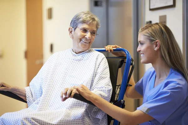 Äldre skjuts kvinnlig patient i rullstol av sjuksköterska — Stockfoto