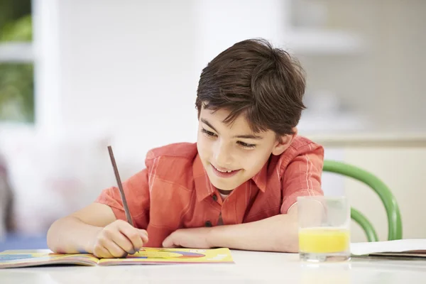 Latino jongen huiswerk in keuken — Stockfoto