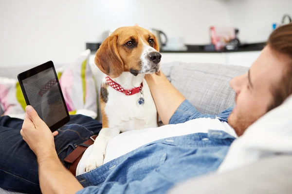 Hombre joven con perro sentarse en el sofá — Foto de Stock