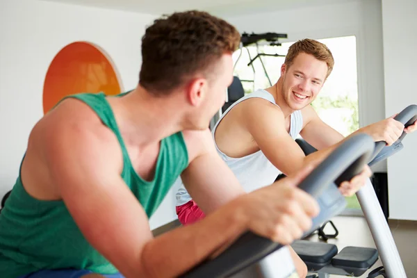 Los hombres de entrenamiento en el gimnasio en las máquinas de ciclismo —  Fotos de Stock