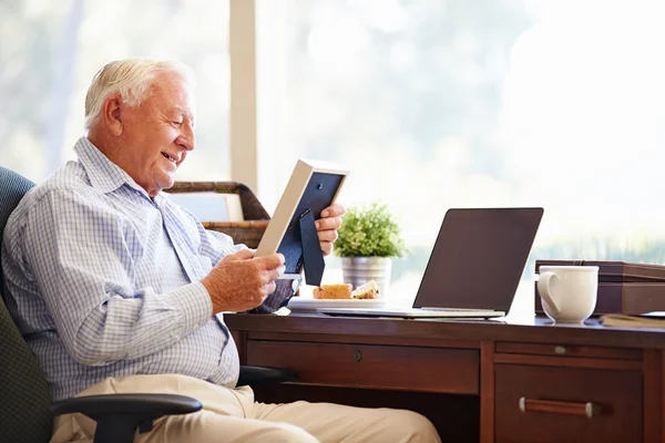 Senior mannen tittar på fotoram — Stockfoto