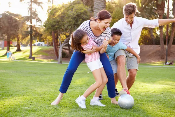 Familj spelar fotboll i parken — Stockfoto