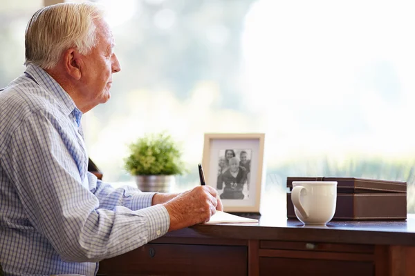 Homme âgé écrivant des mémoires dans le livre — Photo