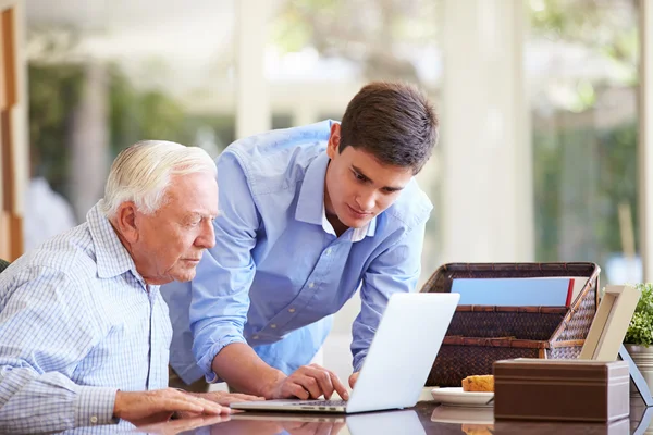 Подросток помогает дедушке с ноутбуком — стоковое фото