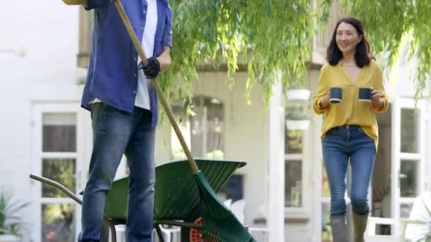 Volwassen Aziatische Man Harken Opruimen Bladeren Tuin Als Vrouw Brengt — Stockvideo