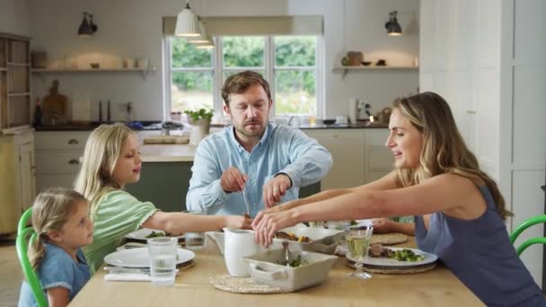 Föräldrar Som Serverar Mat Som Familj Sitter Runt Bordet Hemma — Stockvideo