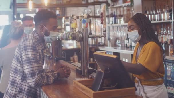 男性顾客在酒吧里戴口罩 为健康大流行病期间的饮料支付非接触式费用 — 图库视频影像