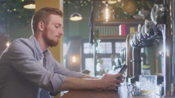 Boldogtalan Férfi Kocsmában Egyedül Iszik Egy Pohár Whiskyvel Üzenetet Küld — Stock videók