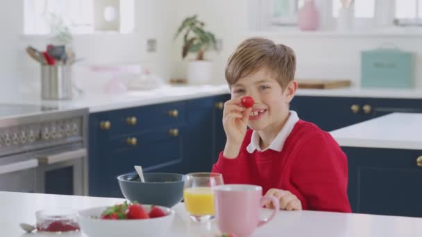 Γέλιο Αγόρι Φορώντας Σχολική Στολή Στην Κουζίνα Βάζοντας Φράουλα Στη — Αρχείο Βίντεο