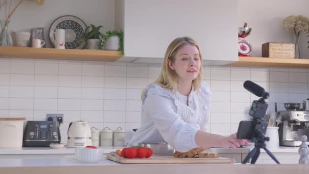 女性のブログは 携帯電話上の台所で家庭での食品についてのソーシャルメディアビデオを作る スローモーションで撮影 — ストック動画